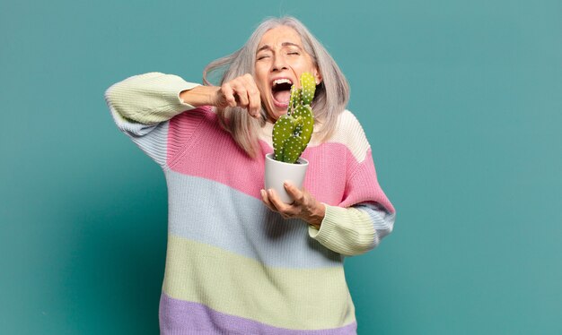 Bella donna con i capelli grigi con un cactus