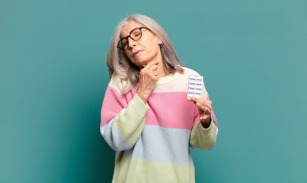 Foto donna graziosa dei capelli grigi con le pillole di malattia