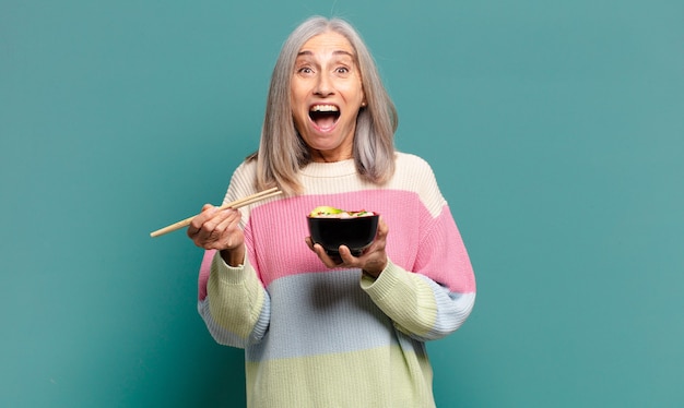 Bella donna dai capelli grigi con una ciotola di ramen