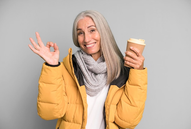 Gray hair senior pretty woman wearing an anorak with a take away hot coffee winter and cold concept