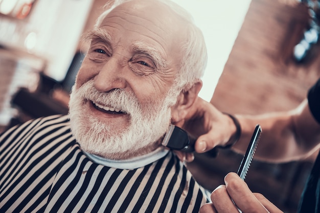 Gray Haired Adult Smiles tijdens het knippen van de nek.