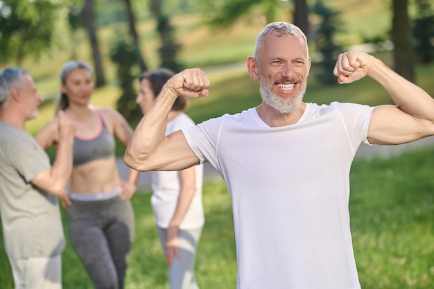 A gray-haired bearded mid aged man feeling positive and happy