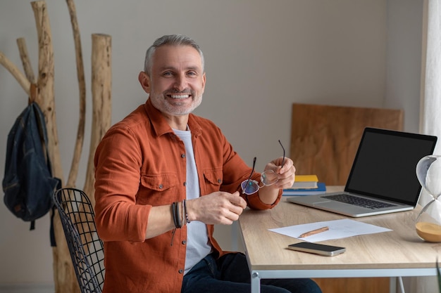 A gray-haired man in orange shirt looking happy