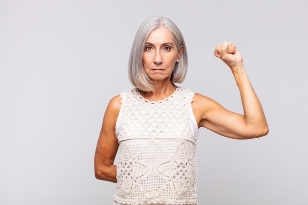 Donna dai capelli grigi che si sente seria, forte e ribelle, alza il pugno, protesta o combatte per la rivoluzione