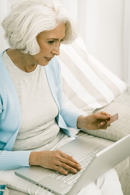 Серая с волосами женщина использовать ноутбук для покупок в Интернете или банковского дела