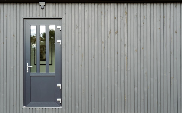 Gray house door with glass on gray painted board wall copy space