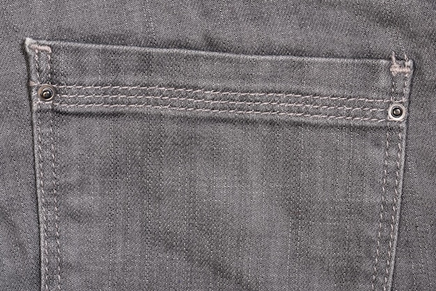 Primo piano della tasca dei jeans grigi su sfondo grigio dei jeans