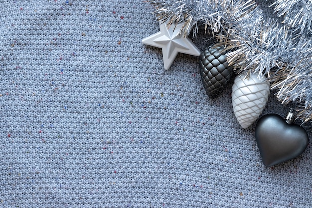 Gray knitted texture with silver tinsel garland and Christmas tree toys