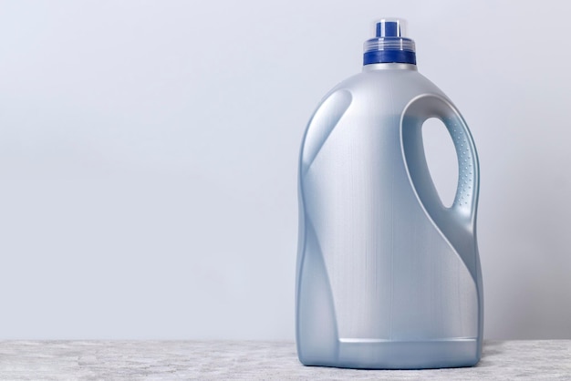 Gray large plastic bottle for liquid laundry detergent against the wall with copy space