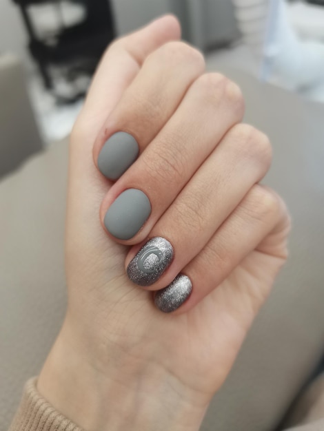 Gray manicure processed nails in salon salon coating gel polish gray manicure on white hands Russia