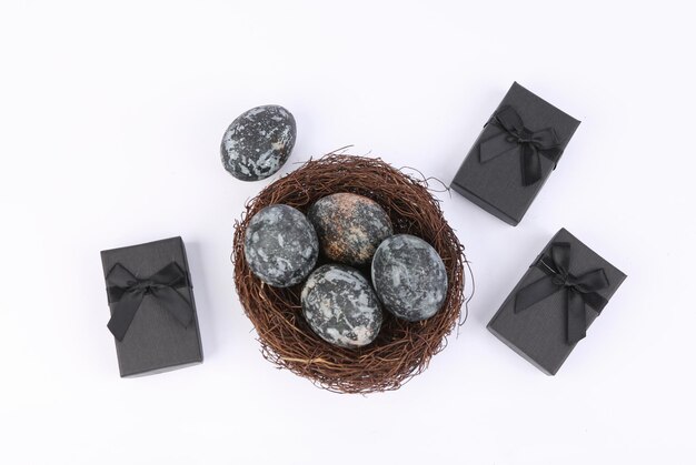 Gray marble painted Easter eggs in nest and gift boxes on white background