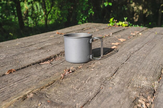 Photo gray metal cup in nature on a wooden table