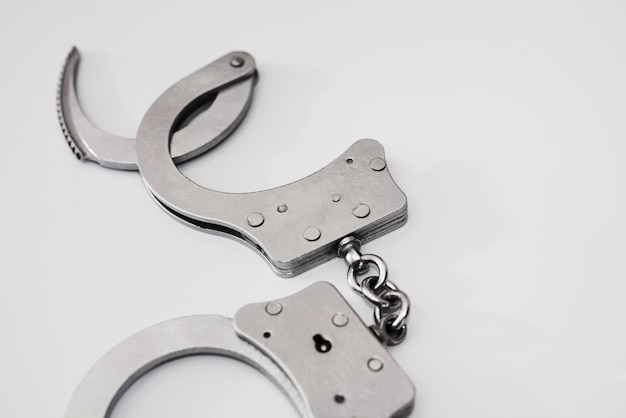 Gray metal handcuffs on a white background. Crime concept.