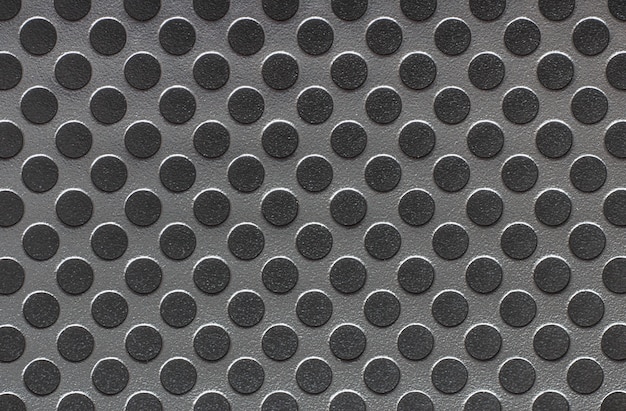 Gray metal surface with black circles.