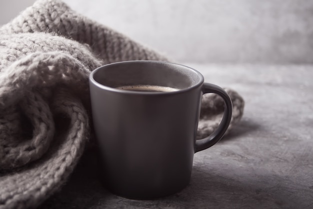 コーヒーと灰色のテーブルの上の灰色のスカーフの灰色のマグカップ