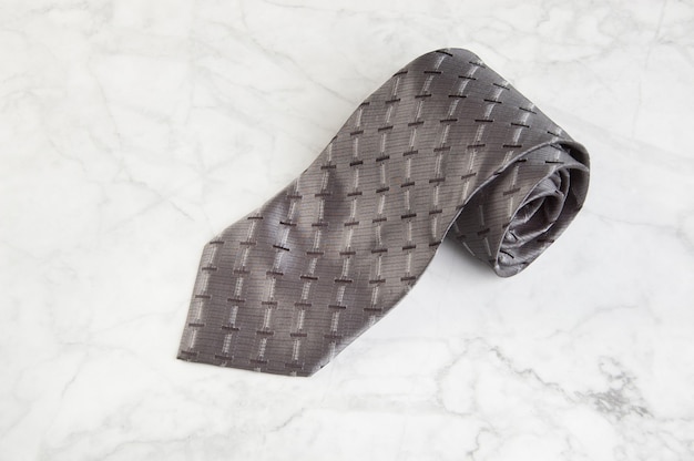 Gray neck tie on marble background. Copy space for text.