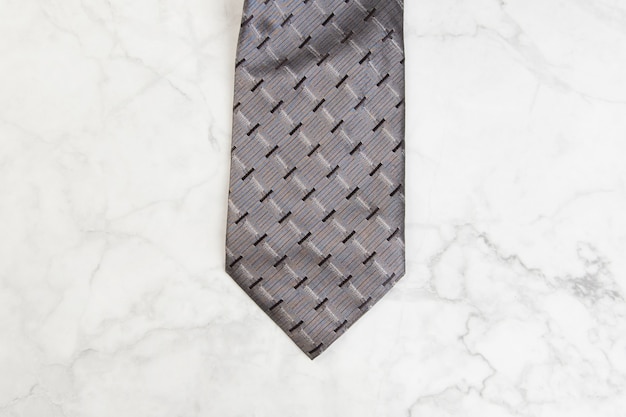 Gray neck tie on marble background. Copy space for text.