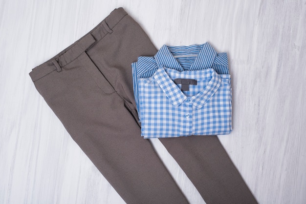 Gray pants and blue shirts on wooden background. Fashionable concept