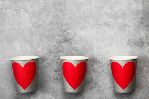 Gray paper cups for drinks with red heart on a light background. Top view, copy space