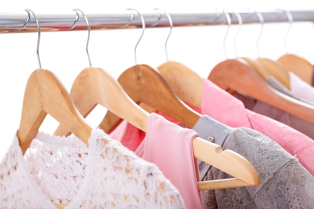 Vestiti delle donne grigie e rosa su portabiti in legno su un rack su sfondo bianco. guardaroba femminile