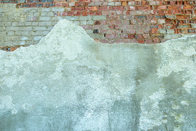 Gray plastered old brickwall with chipped stucco pieces grunge red and white brick wall with damaged...