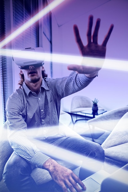 Gray and purple background against male executive using laptop
and virtual reality headset in waiting room