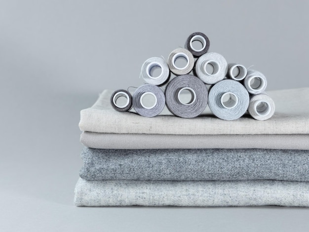 Gray sewing thread spools and fabrics on a gray background