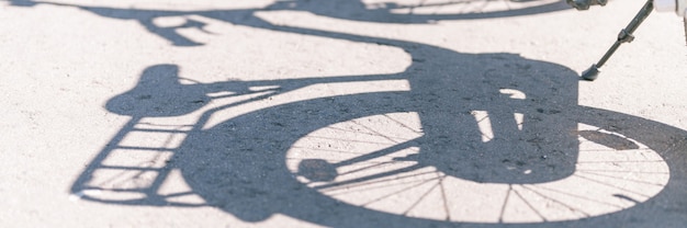 The gray shadow of a child's two wheeled bicycle or bike on the asphalt on a sunny day