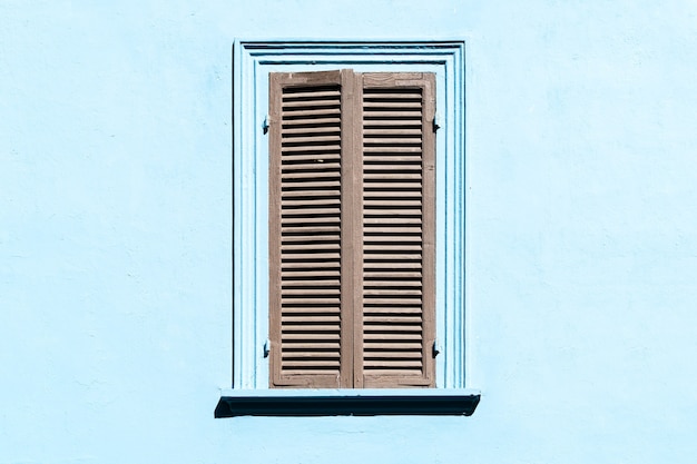 Gray shutters on the window against a blue colored wall