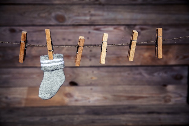 木製の壁に洗濯バサミが付いた灰色の靴下