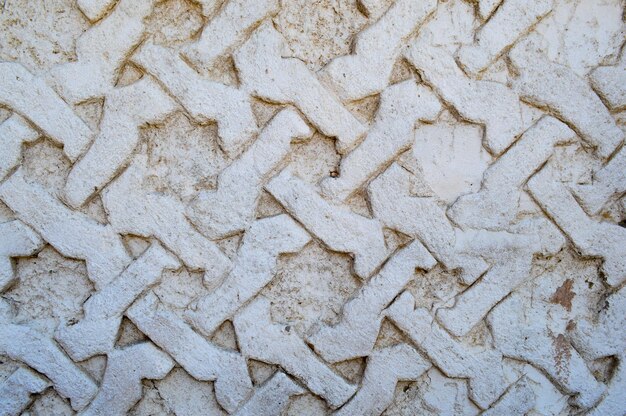 Серая текстурированная бетонная старая цементная резная выпуклая стена с орнаментами с палочками и узорами