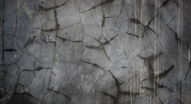 a gray wall with black stains and stains.