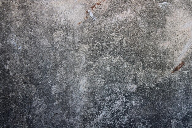 A gray wall with a rough textured surface and a stain on it.