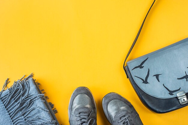 Gray with silvery female sneakers, scarf and bag on a bright yellow background