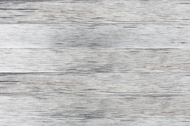 木目テクスチャを示す色あせた白いペンキで風化した苦しめられた素朴な木の灰色の木製の背景