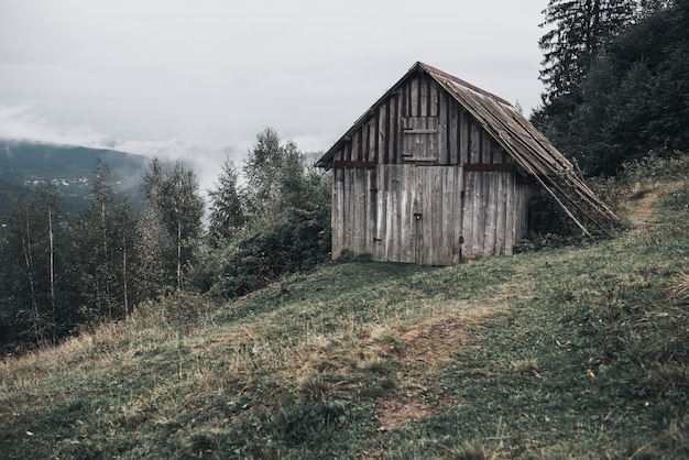 Casa in legno grigia con assi nelle montagne dei carpazi. yaremche. nebbia sulla foresta.