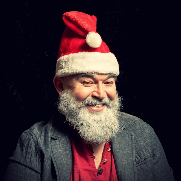 Photo the graybearded jolly old man in a santa claus hat