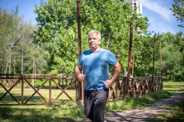 grayhaired man 50 years old jogging in the park in summer