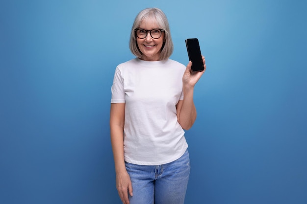 Grayhaired's vrouw beheerst smartphonegadget op heldere studioachtergrond