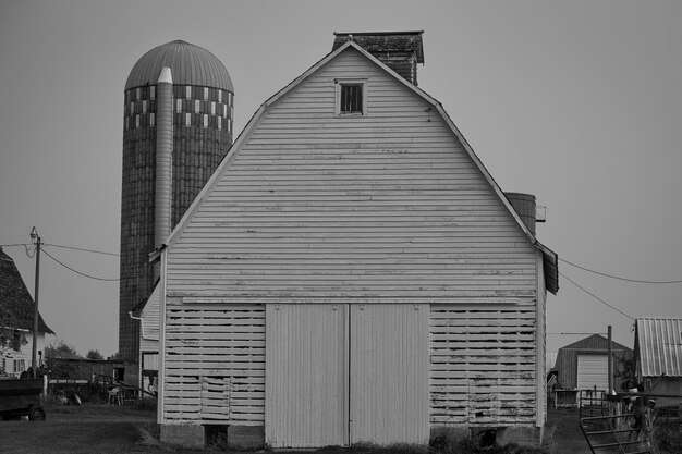 A grayscale of a barn in a farm