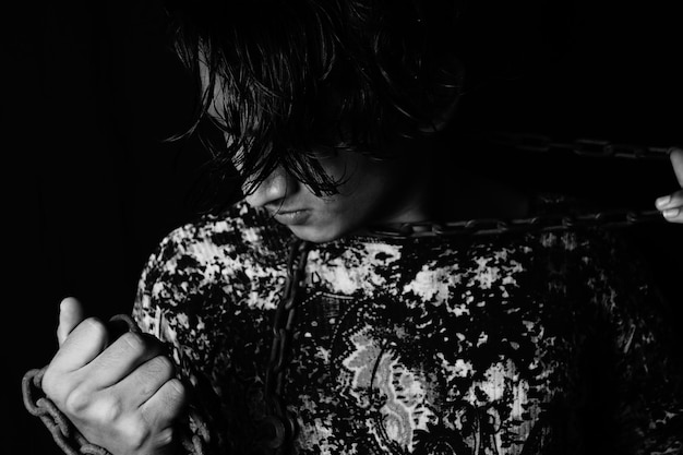 Grayscale portrait of an angry asian man with a metal chain around his neck