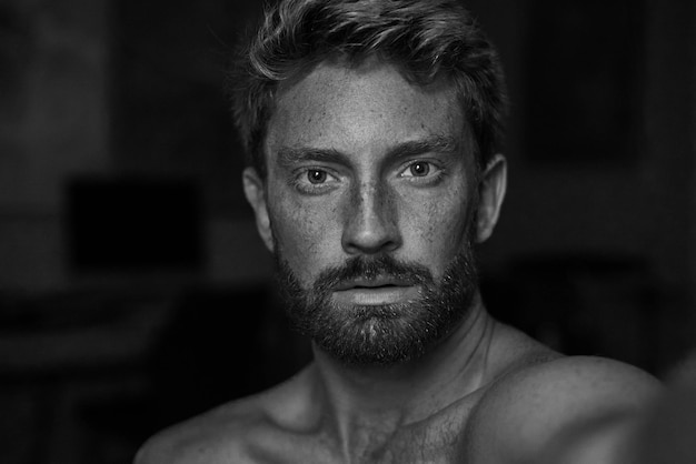 Grayscale portrait of an athletic man with freckles and a beard