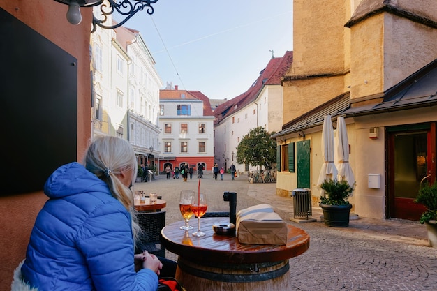 Graz, austria - 16 febbraio 2019: donna al caffè o al ristorante di strada sulla piazza franziskanerplatz a graz. paesaggio urbano con turisti che bevono nella città vecchia di graz in austria. stiria in europa.