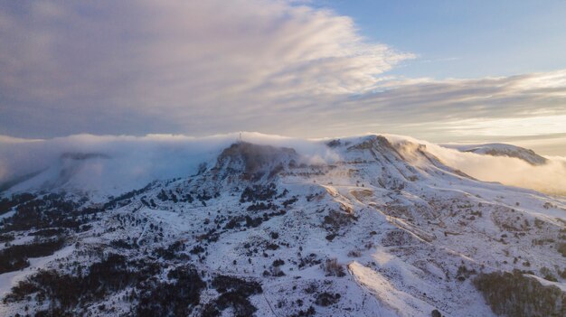 日光の下で雪に覆われた巨大な岩の素晴らしい空中山の景色。絵のようにゴージャスなシーン。