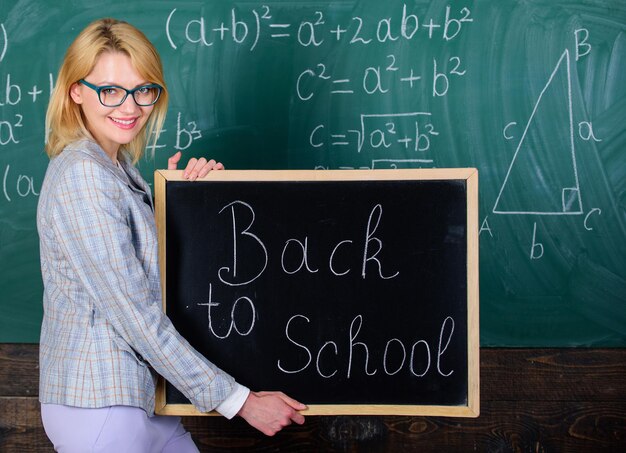 Photo great beginning of school year. top ways to welcome students back to school. teacher woman hold blackboard inscription back to school. it is school time again. school teacher happy welcome pupils.