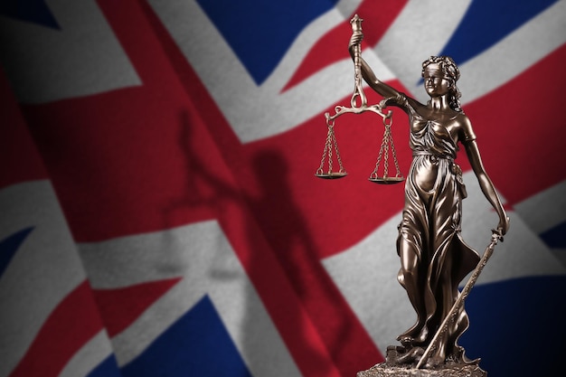 Great britain flag with statue of lady justice and judicial scales in dark room Concept of judgement and punishment