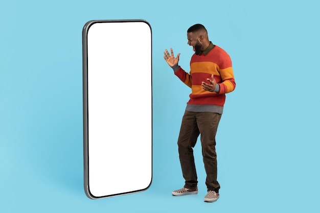 Great Deal Excited Black Male Looking At Big Blank Smartphone With Amazement