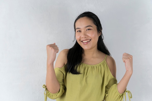 Great deals An Asian girl in a cheerful green shirt points to a handful of invisible objects pose over a gray background