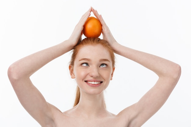 Great food for a healthy lifestyle. Beautiful young shirtless woman holding piece of orange standing