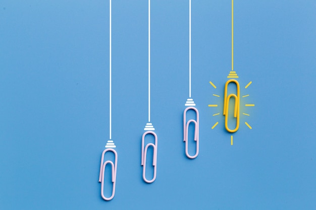 Concetto di grandi idee con graffetta, pensiero, creatività, lampadina su fondo blu, nuovo concetto di idee.